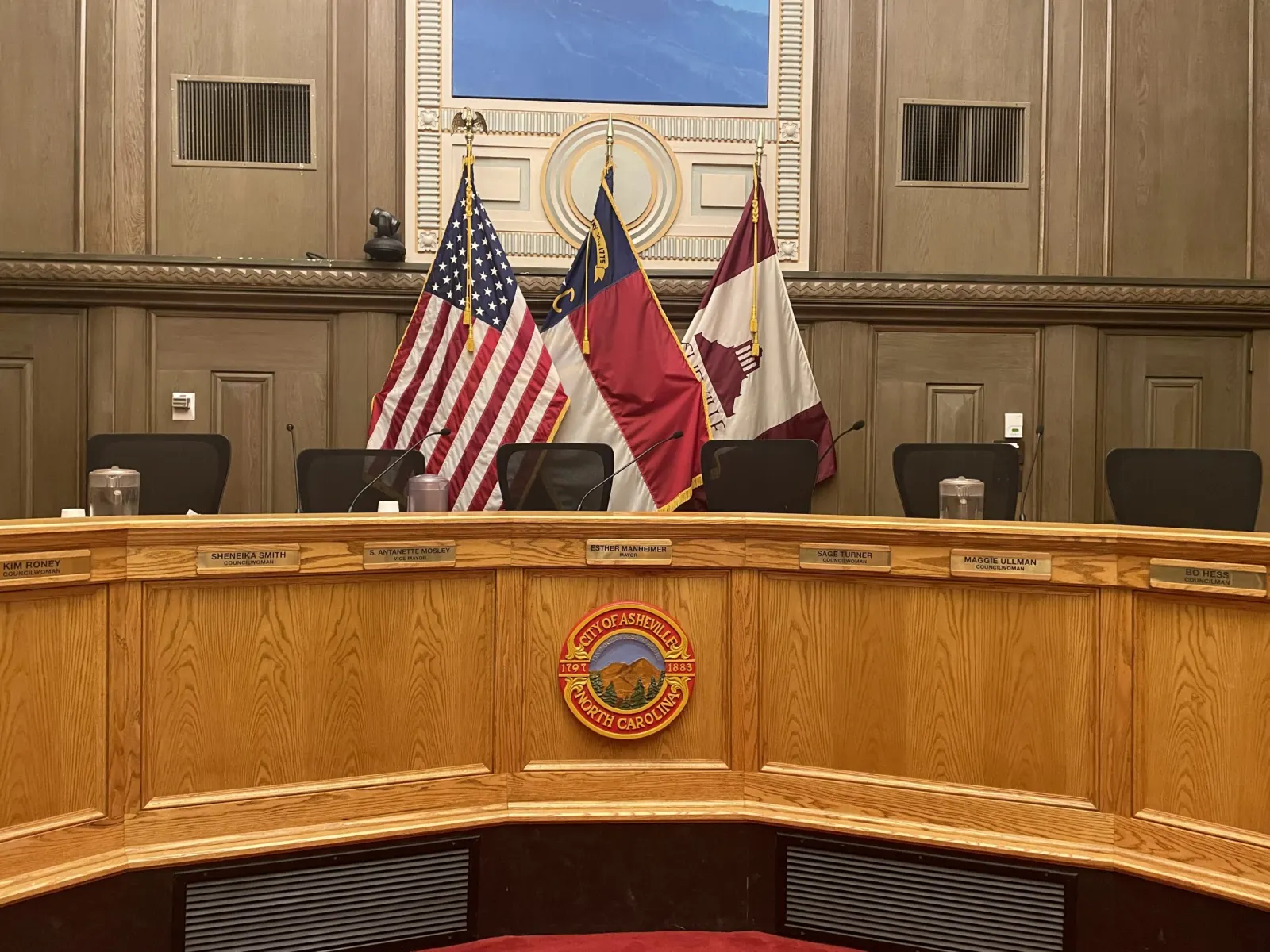 The empty City Council dais, with the U.S., North Carolina and Asheville flags behind it.